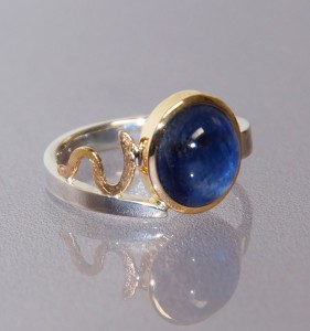 blue sapphie cabochon in a yellow gold setting with a silver band